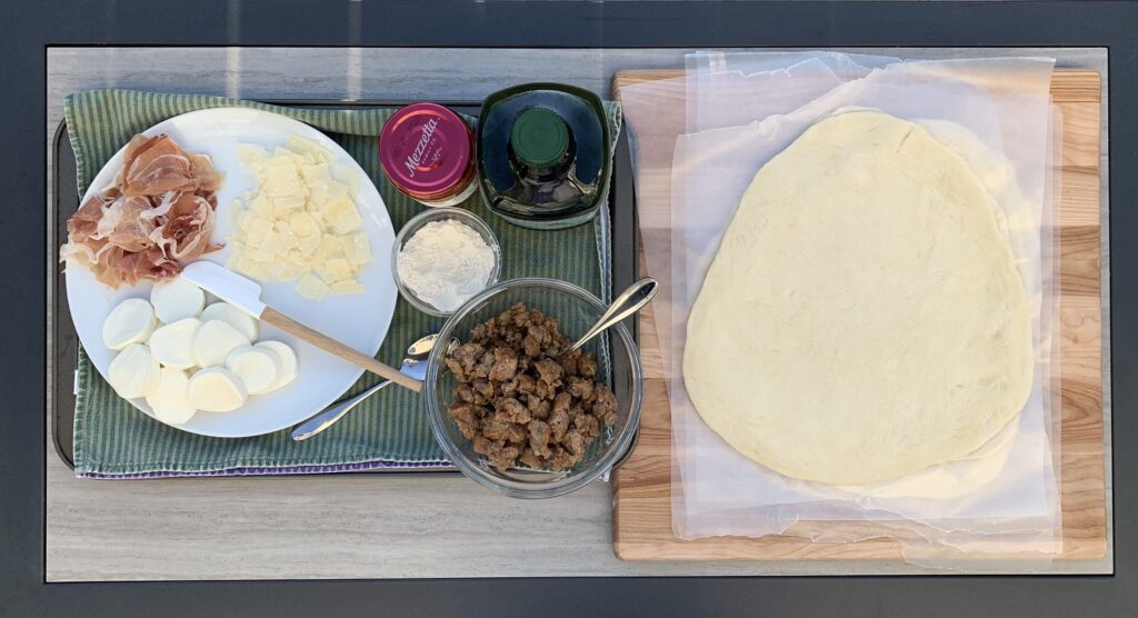 Rolled out pizza dough, pizza sauce and cheese and meat toppings