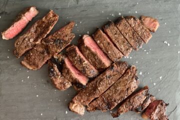 Black slate board with two steaks cut in slices